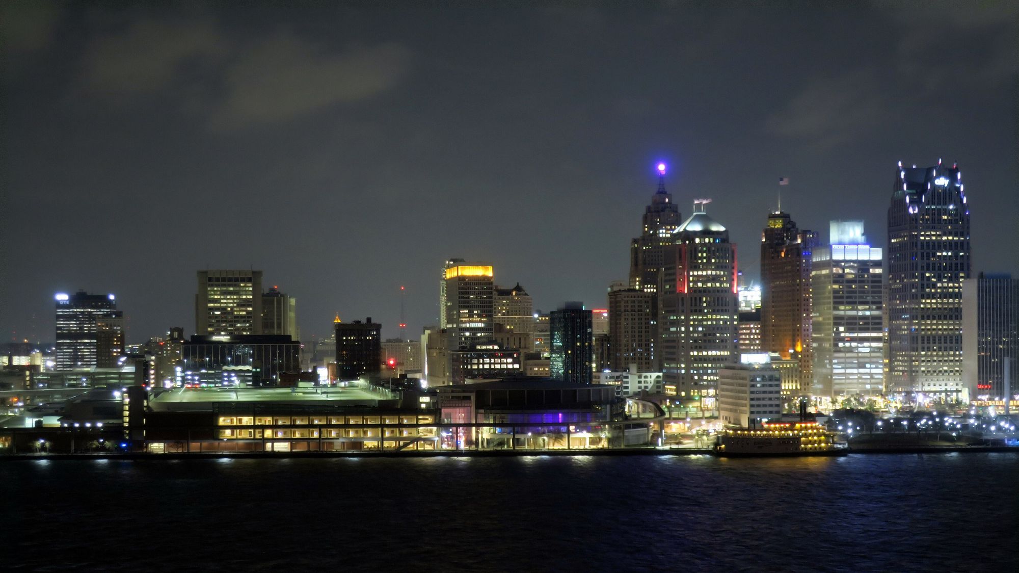 A city skyline lit up at night across the river